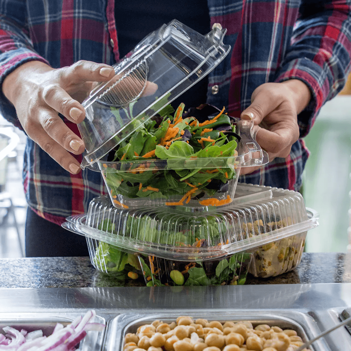 man holding clear compostable clamshells