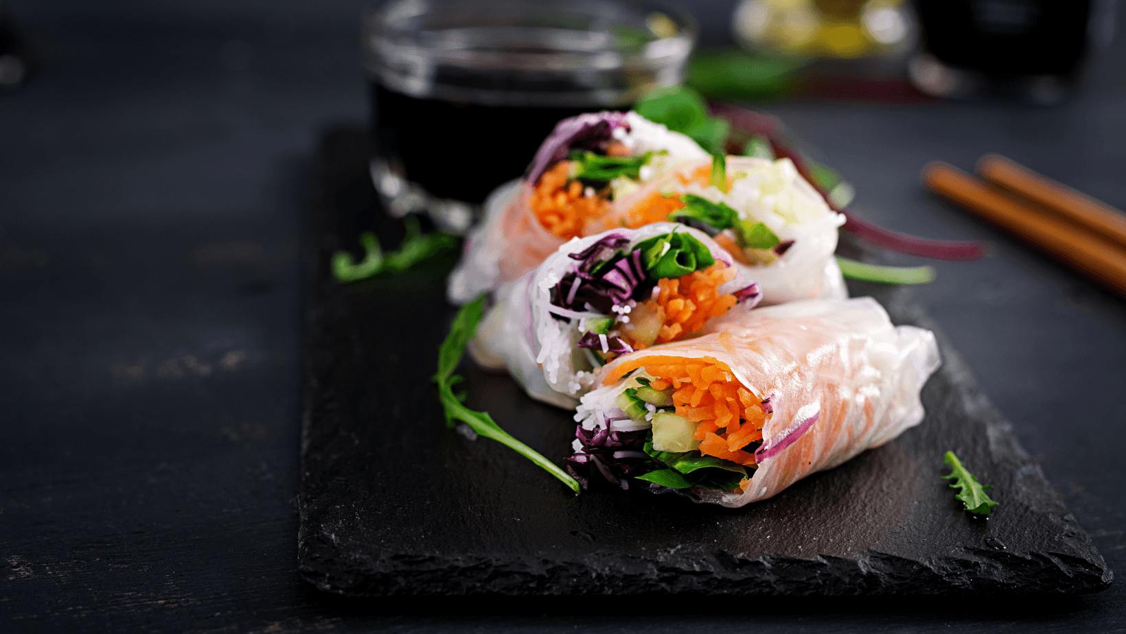 Vegetarian vietnamese spring rolls with spicy sauce, carrot, cucumber, red cabbage and rice noodle. Vegan food. Tasty meal.