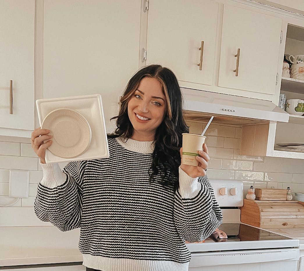 woman holding compostable plates and cup