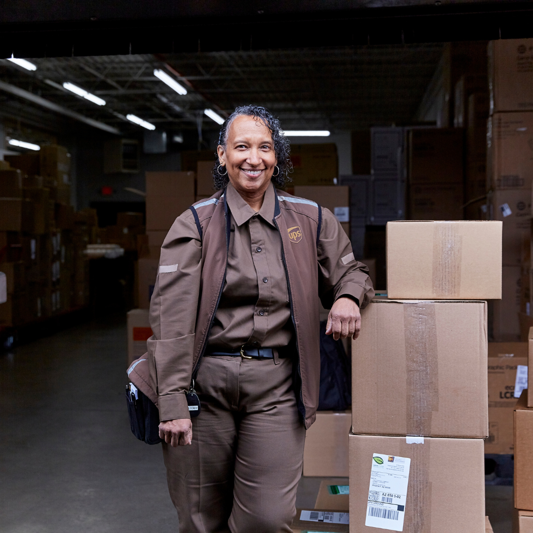 UPS Driver stands next to a stack of boxes