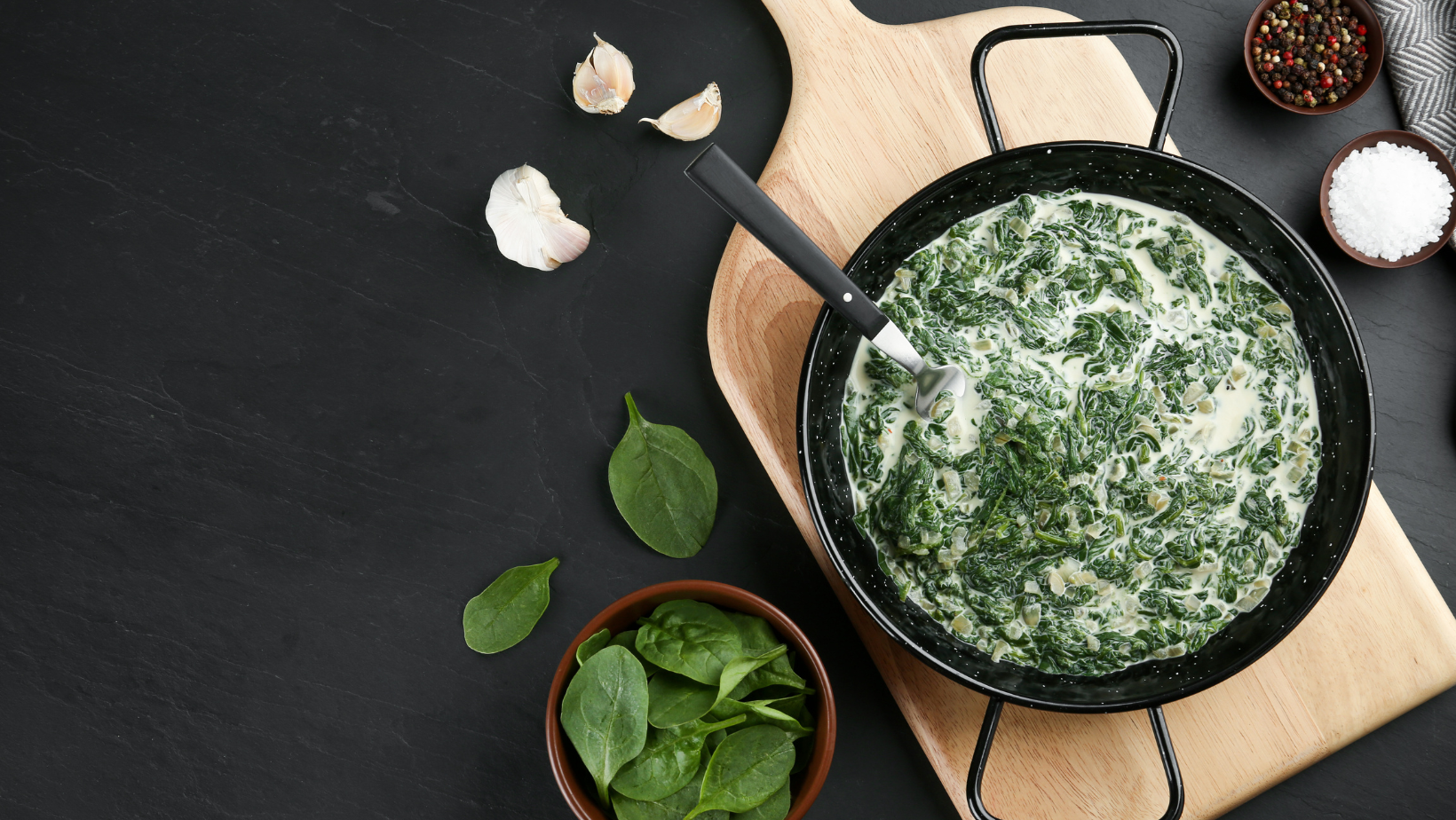 Tasty spinach dip in frying pan on black table, flat lay. Space for text