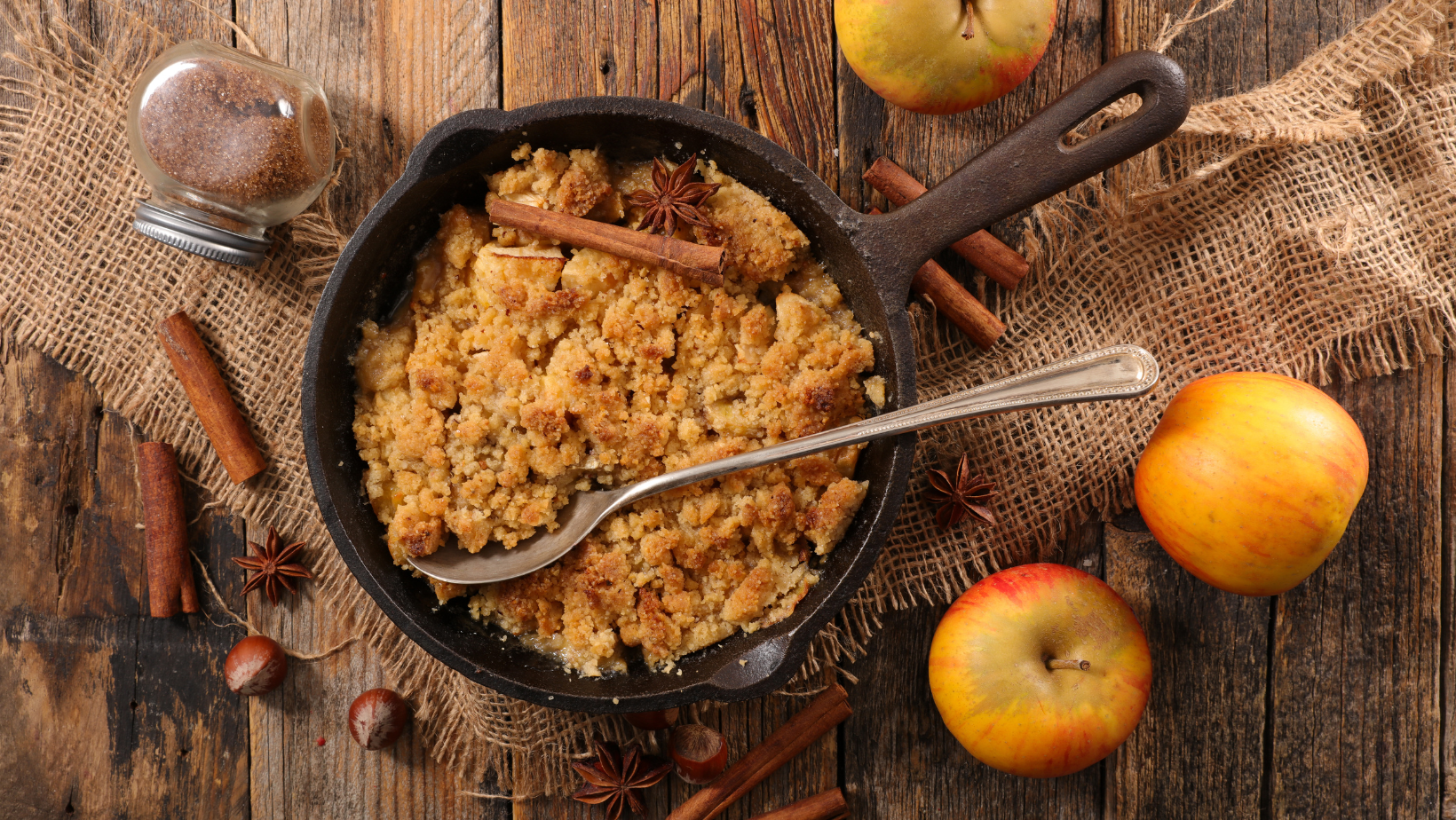 homemade apple crumble sitting on a wooden table in a cast iron pan