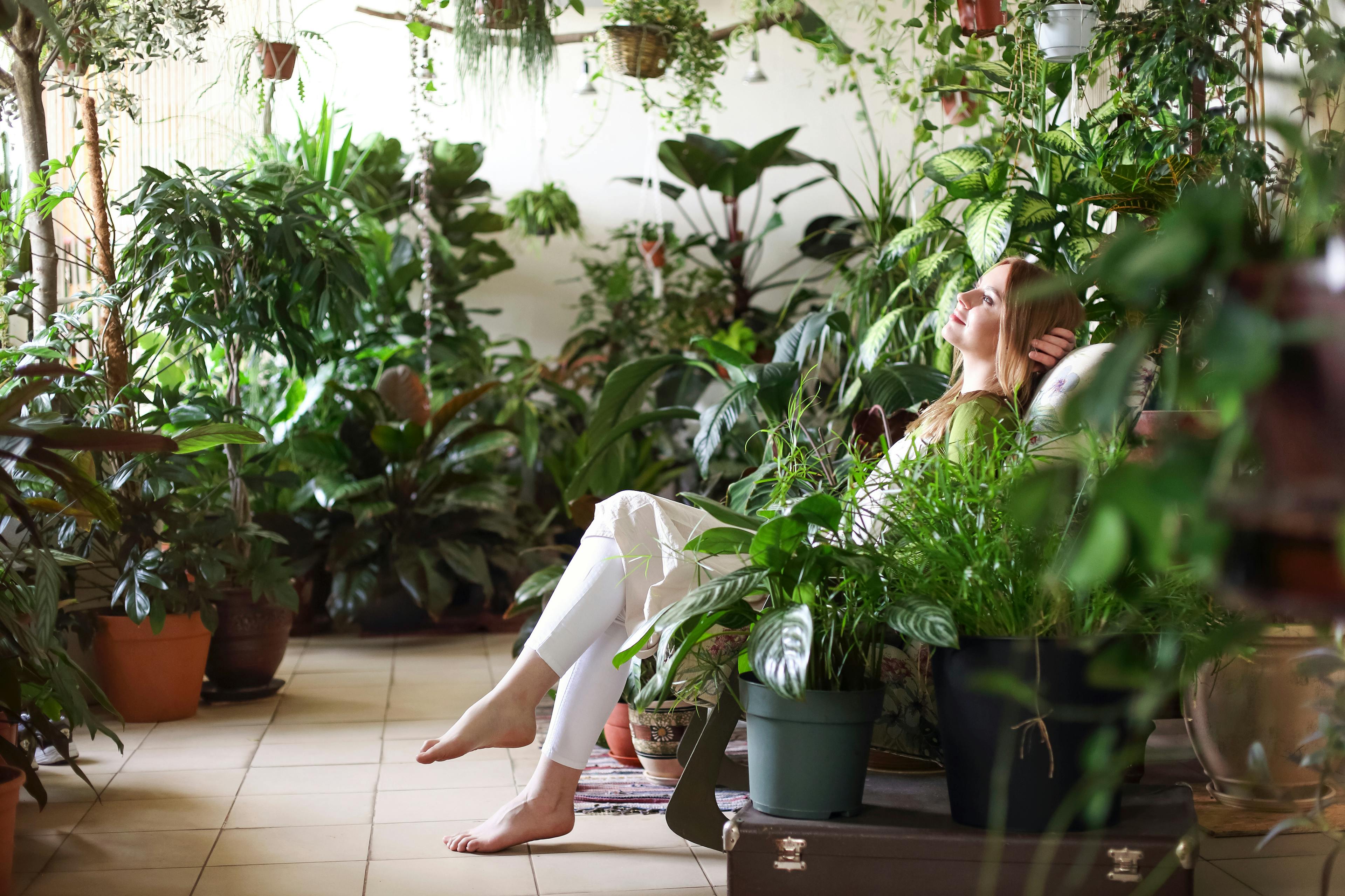 A woman sits in a room filled with indoor plants